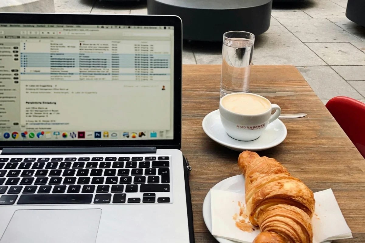 laptop with email open, sitting on a table at a coffee shop