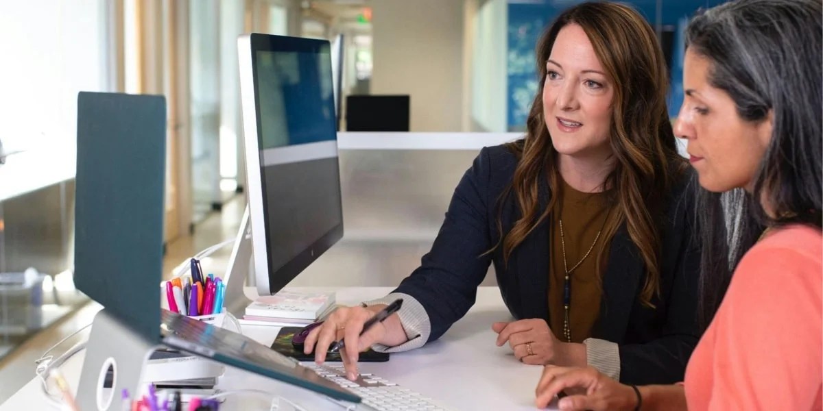 two women working at a desktop computer together