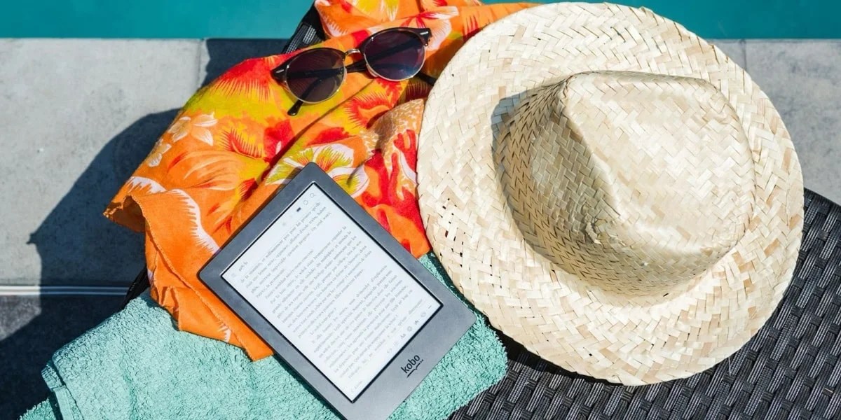 ereader and beach clothes sitting by a pool