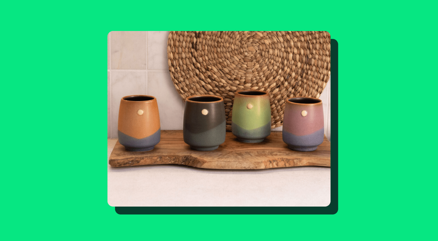 a photo of four pottery mugs on a wooden cutting board on a light green background