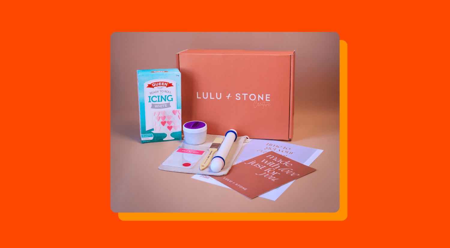 a photo of a cookie making kit and box on an orange-red background